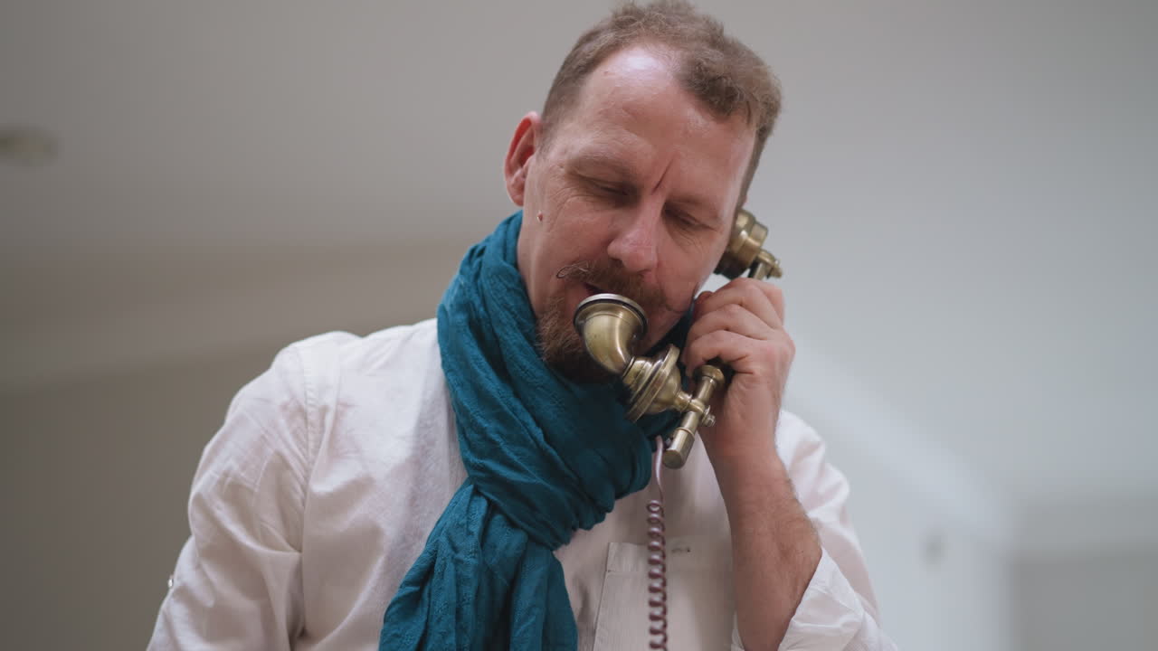 Man artist in scarf talks on vintage phone. Vintage phone adds touch of nostalgia to studio modern setting during brief hiatus from painting session