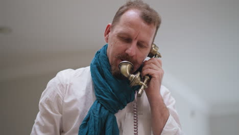 man artist in scarf talks on vintage phone. vintage phone adds touch of nostalgia to studio modern setting during brief hiatus from painting session