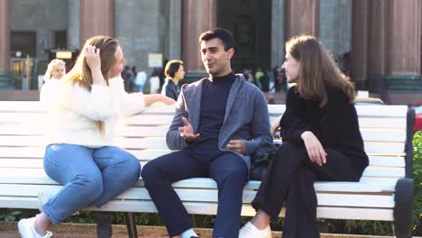 friends talking on a bench in a city park