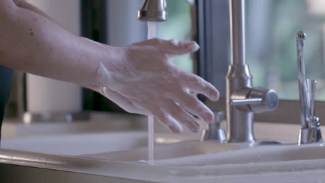 a caucasian male is cleaning his hands in a home kitchen