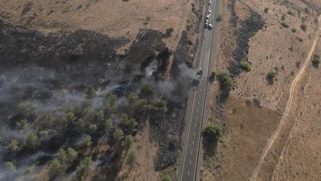 Passenger-bus-on-fire-and-smoking-on-highway-after-accident,-drone-shot-top-view