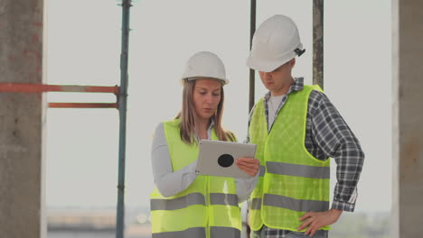 equipo de construcción o arquitecto y constructor o trabajador con cascos discuten un plan de construcción de andamios o un plan o una lista de comprobación