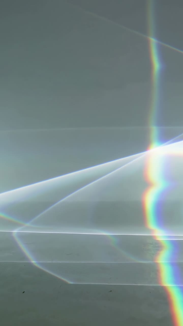 Vertical video: Moving light causing rainbow stripe pulsing on gray with angled bands, copy space