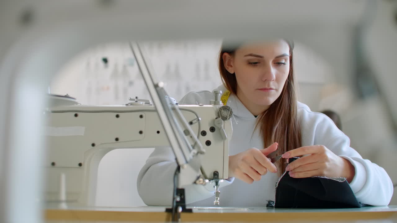 две молодые швейцы работают с тканью в дизайнерском бюро. швейница женщина измеряет кусок ткани с помощью линейки. две молодые портнихи работают с тканей в