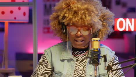 woman singing into microphone in a podcast studio