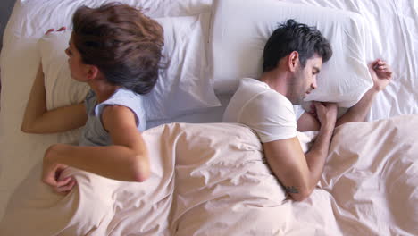 overhead view of couple with relationship problems lying in bed