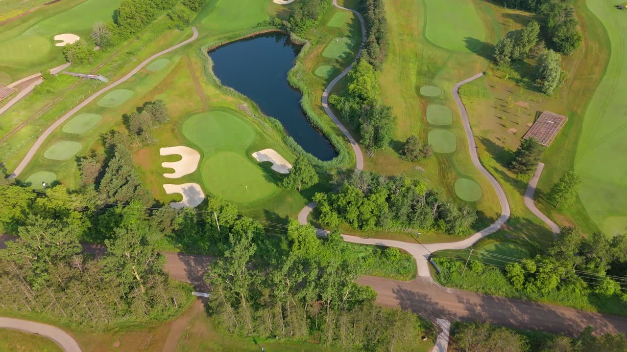 Aerial Flyover Of A Professional PGA Golf Course With A Lake And Lush Fairways. Aerial Flyover