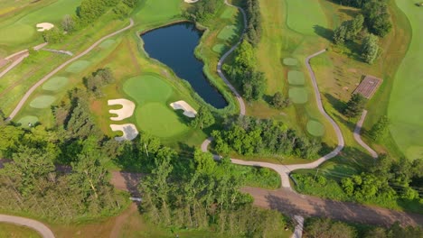 aerial flyover of a professional pga golf course with a lake and lush fairways. aerial flyover