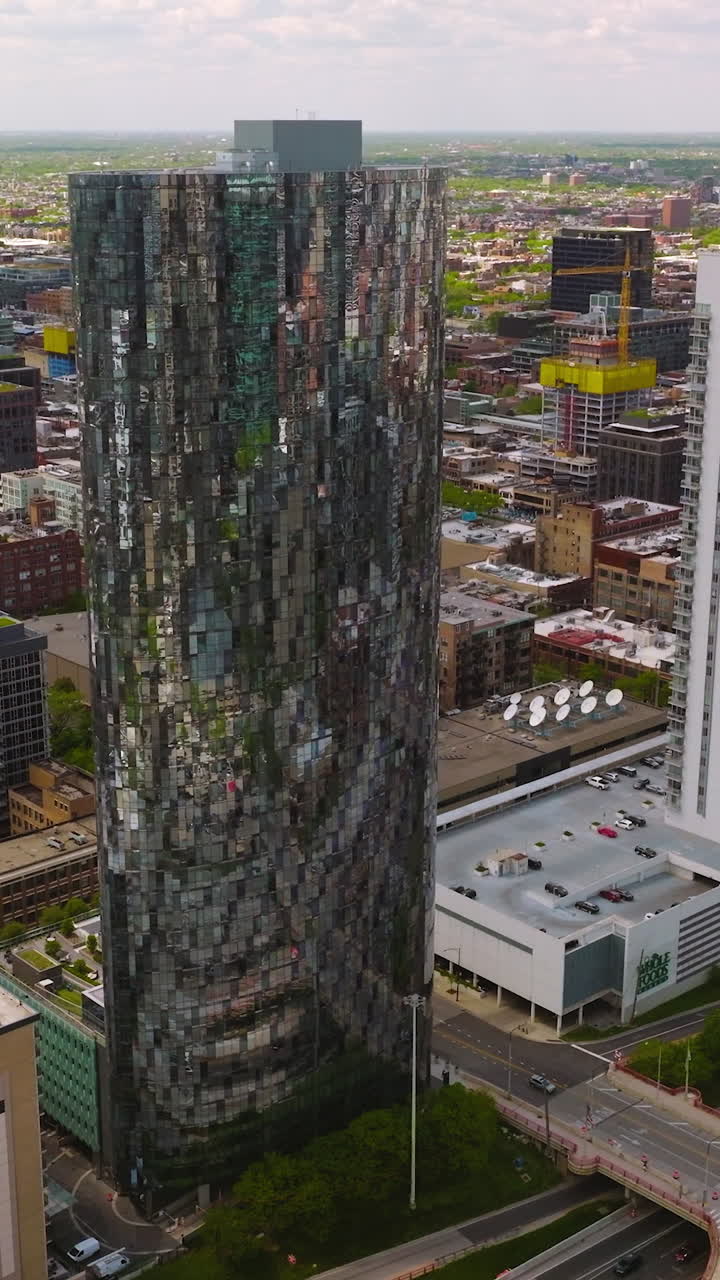 Stunning skyscraper with mirror windows. Multi-lane roads with bridges over and lots of cars. Chicago cityscape at backdrop. Vertical video