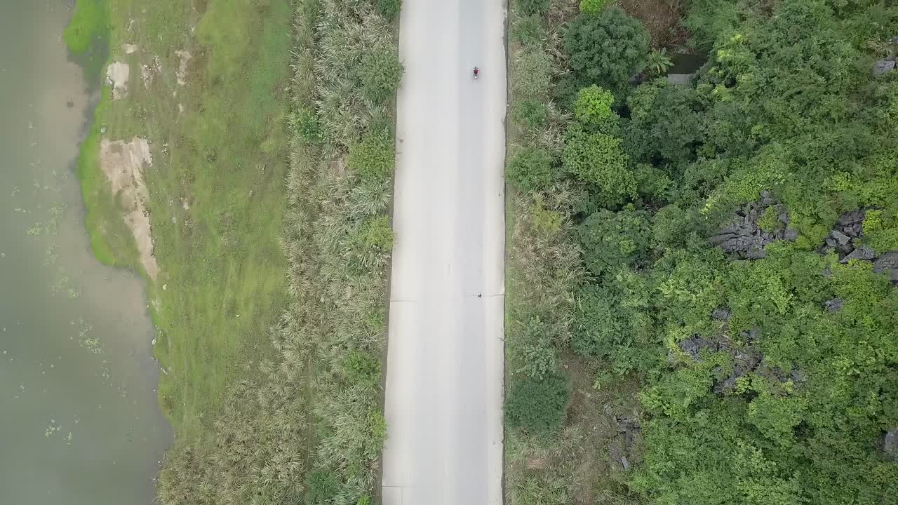 Unique drone follow cam of red motorbiker going over bridge towards  limestone mountains