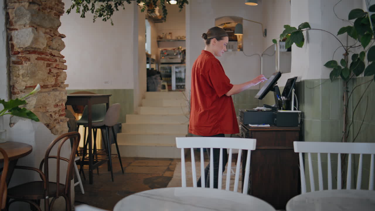 Restaurant worker touching screen digital cashier machine in hall. Woman staff