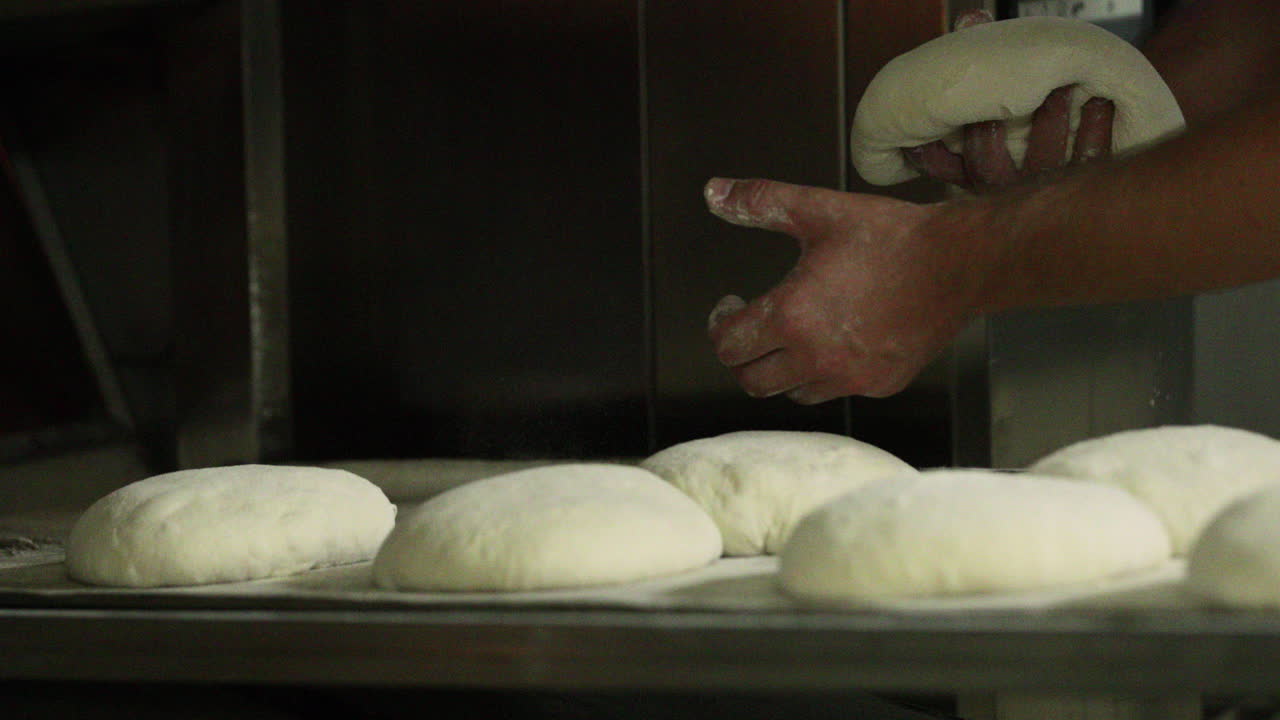 Placing Bread Dough Dusted With Flour On A Baking Tray - close up, slider shot