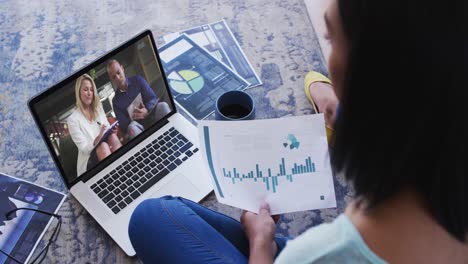 African-american-woman-holding-a-document-having-a-video-call-with-male-and-female-colleagues