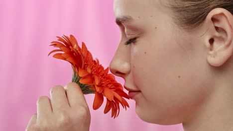 Young Woman with Bright Orange Flower on Vibrant Background a Serene Moment of a Woman Enjoying the Scent of a Vibrant Orange Flower Eyes Closed in Relaxation