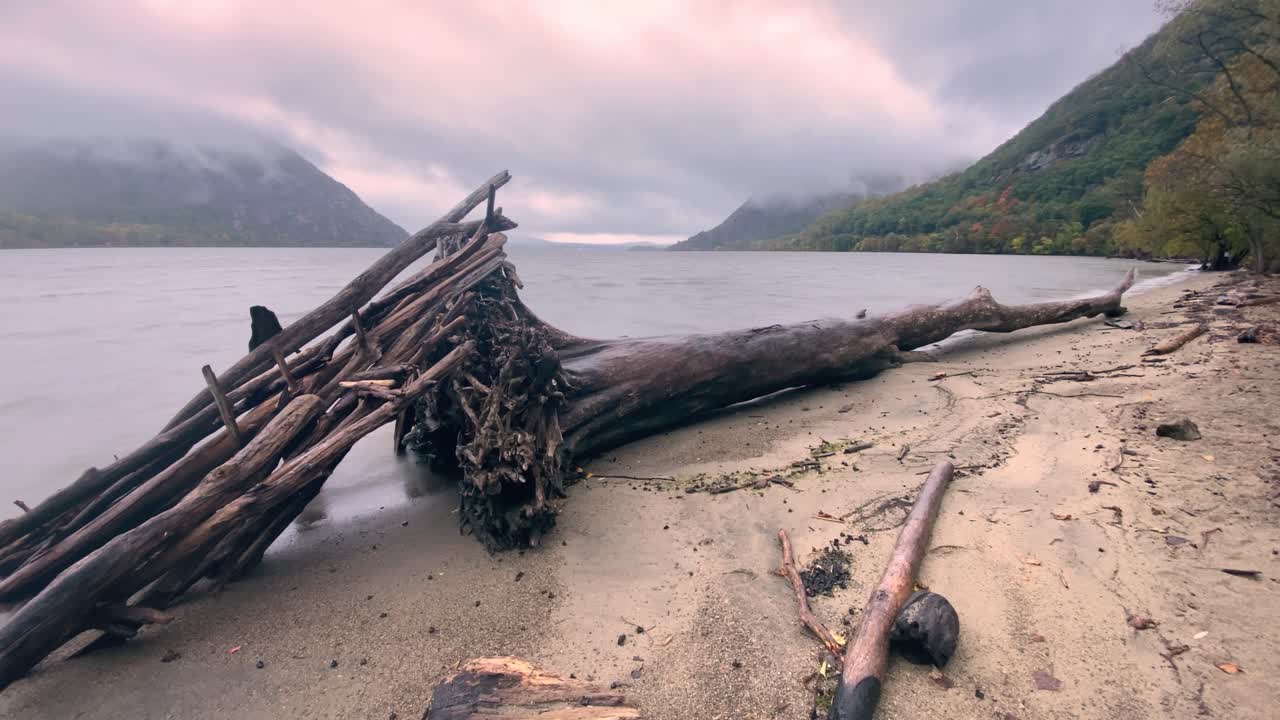 un lapso de tiempo en una playa fluvial con madera a la deriva en primer plano y montañas en el fondo
