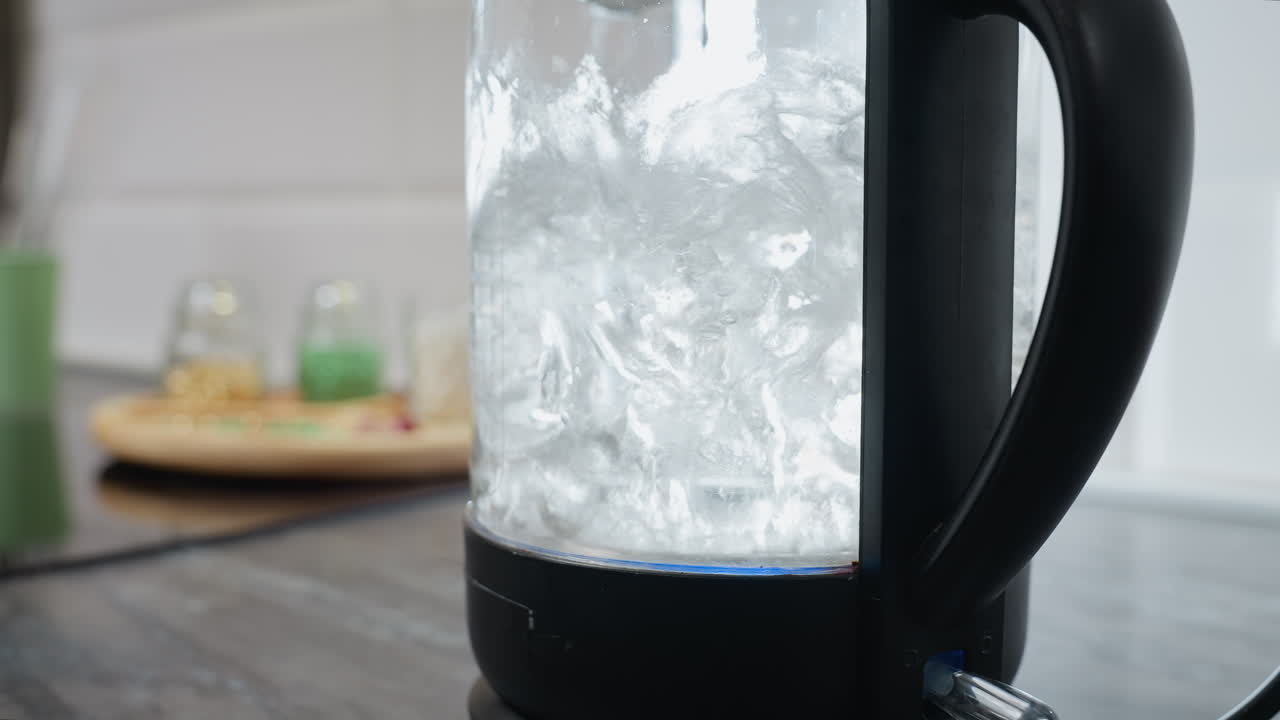 은 푸른 빛과 함께 거품이 형성되고 상승하는 투명한 항아리에서 빠르게 는 물의 근접, 배경에는 다양한 부 장비와 흐릿한 물체가 있습니다.