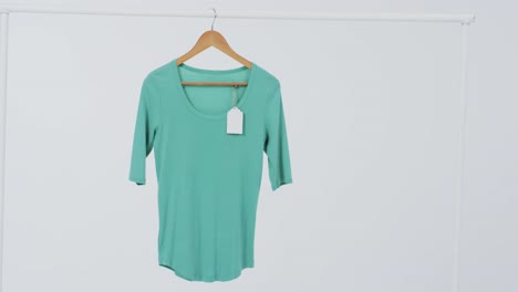 Video-of-green-t-shirt-with-tag-on-hanger-and-copy-space-on-white-background