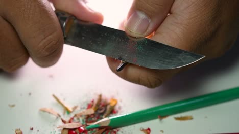 Footage-of-hands-slowly-sharpening-a-pencil-and-some-coloured-pencils-with-a-sharp-knife