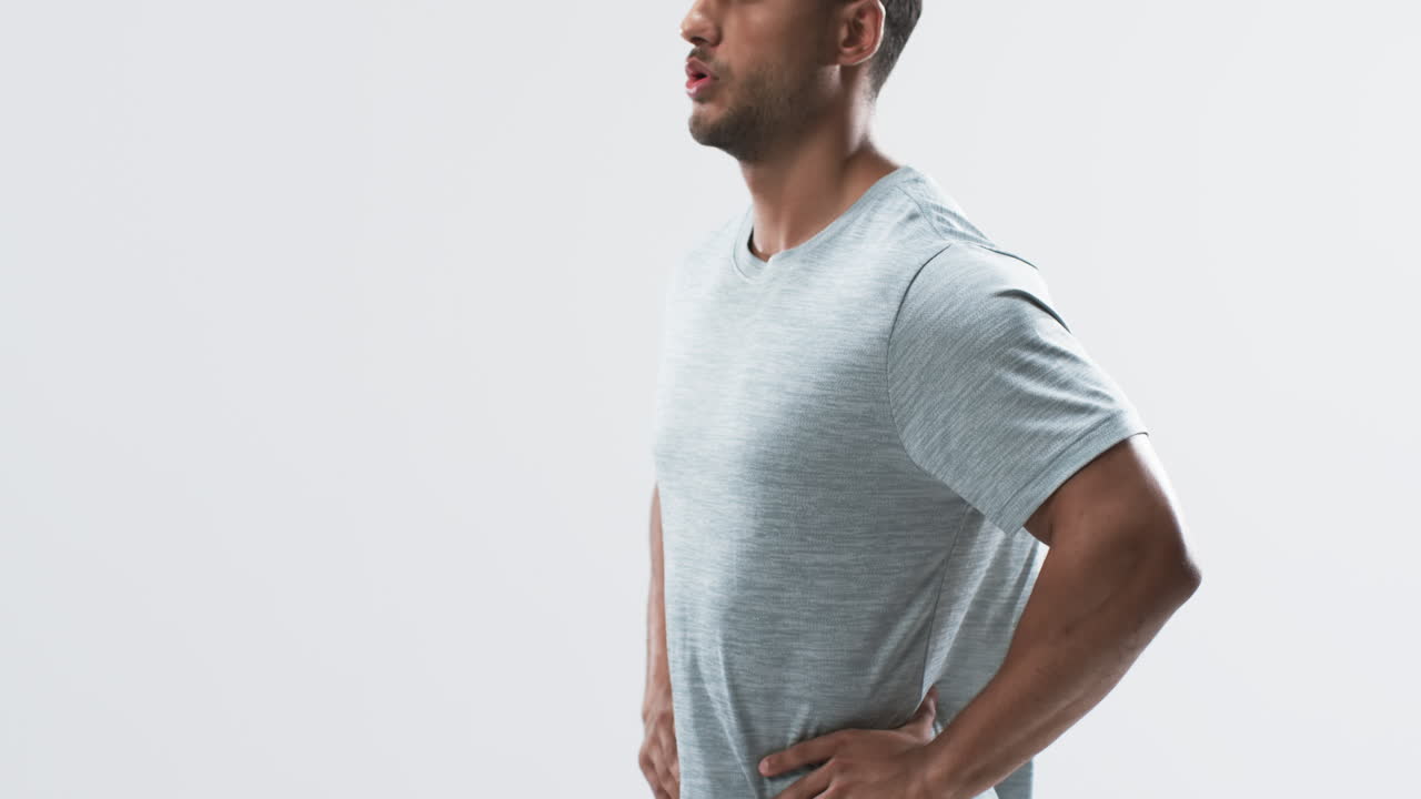 joven atleta biracial de pie con confianza en un estudio en un fondo blanco