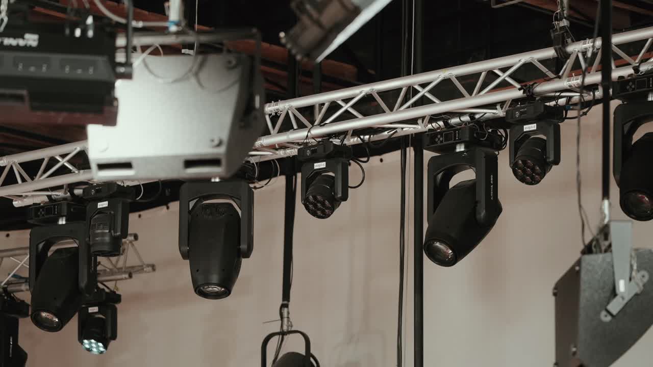 Nærbillede af professionelle scenelys, der hænger fra en metaltruss indendørs.