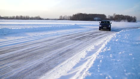 blue suv driving on a snowy road in winter