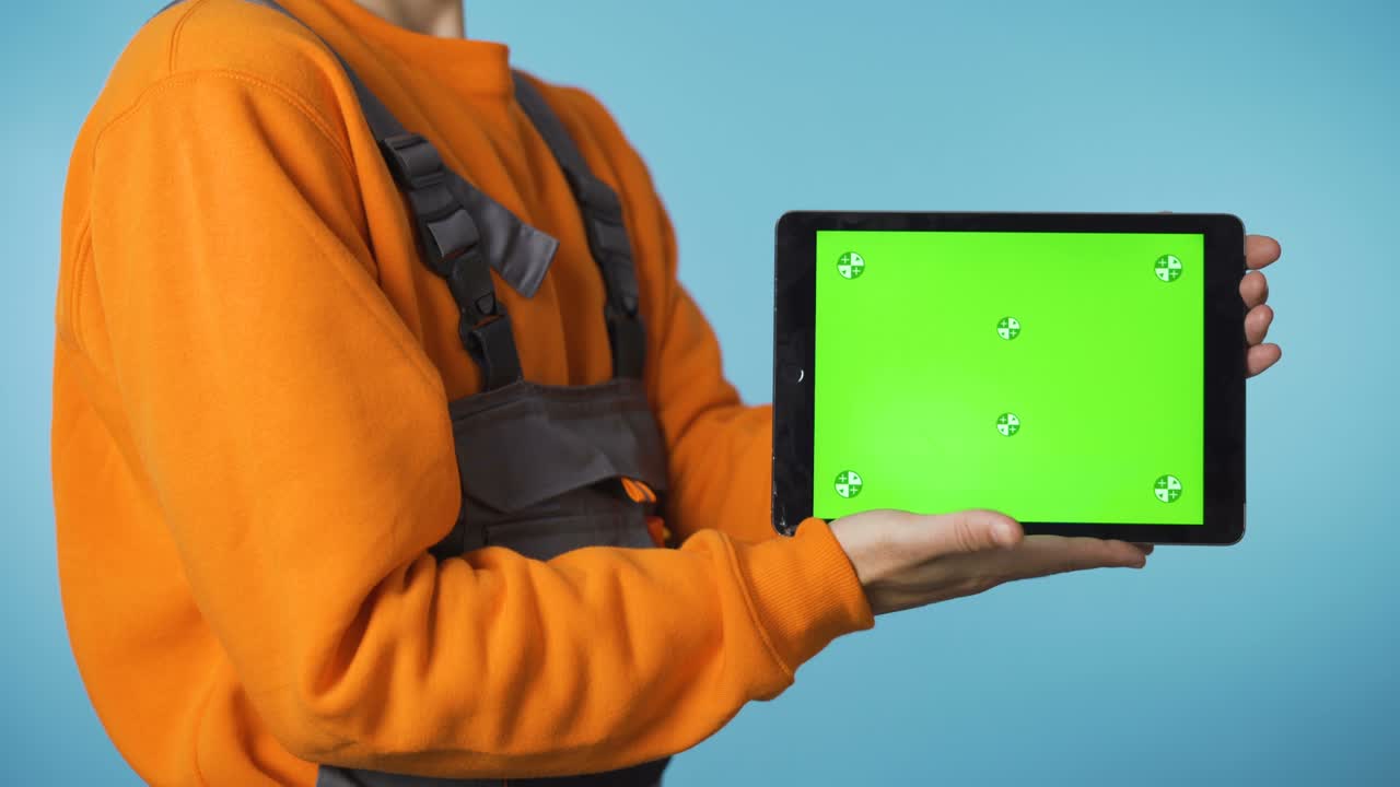 hombre con ropa de trabajo mostrando la tableta de pantalla verde desde abajo