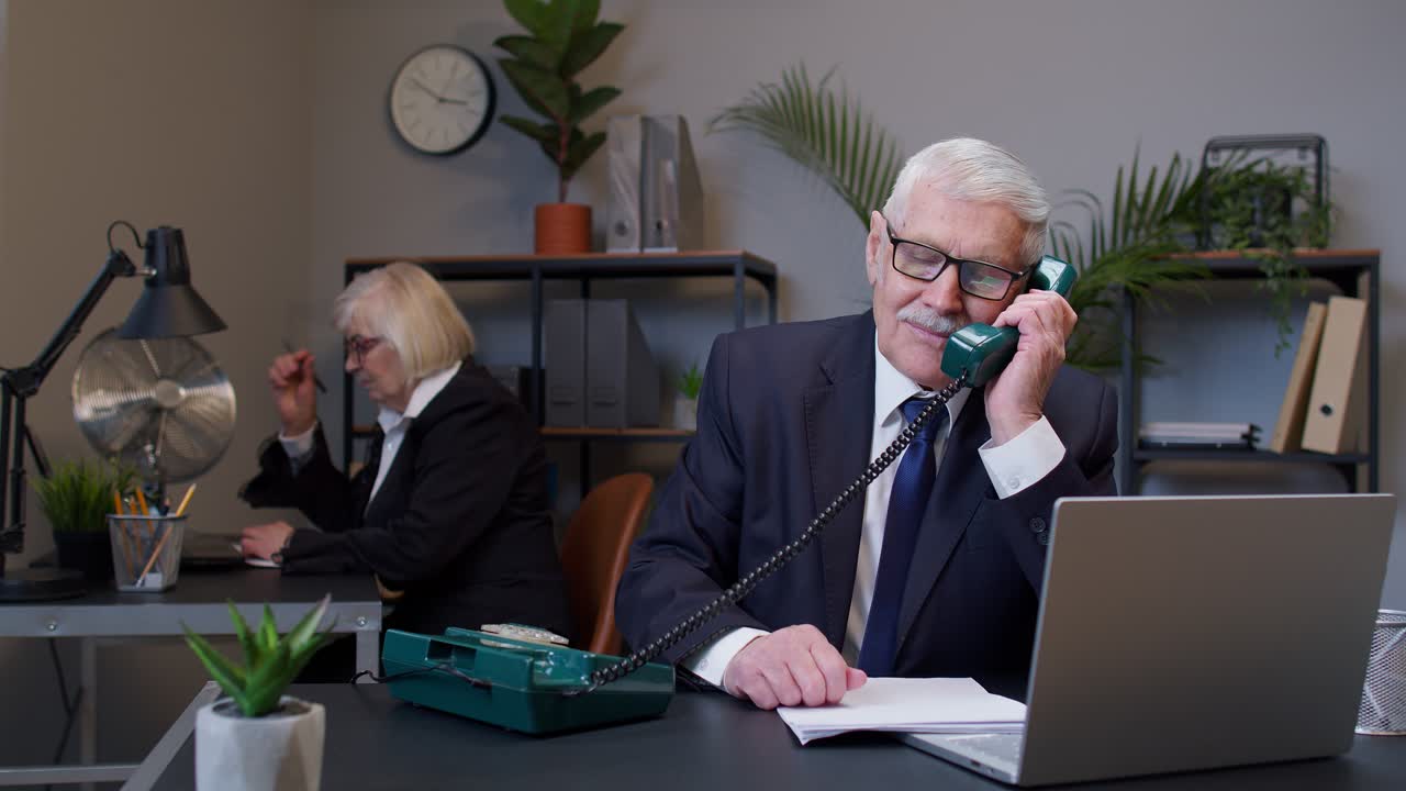 Annoyed senior businessman talking on retro telephone call irritated voice dissatisfied with work