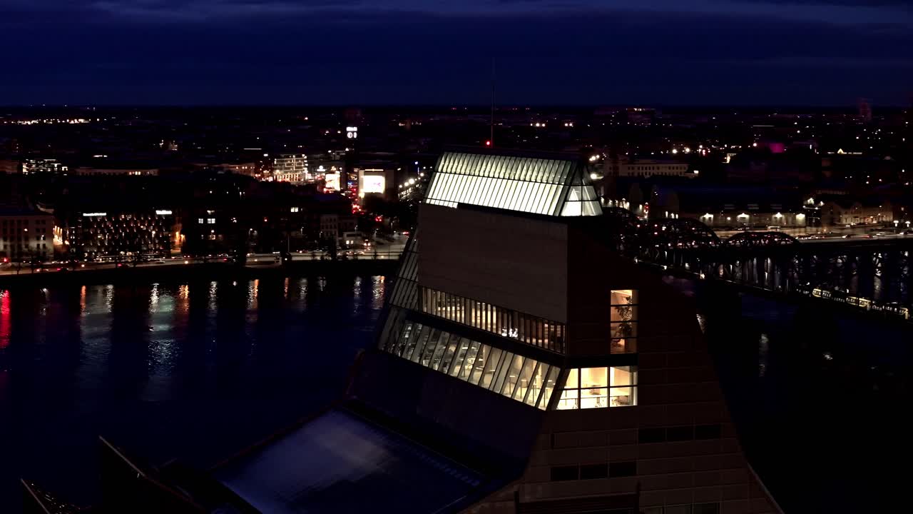 National Library of Latvia glows brightly across river Riga city night timelapse