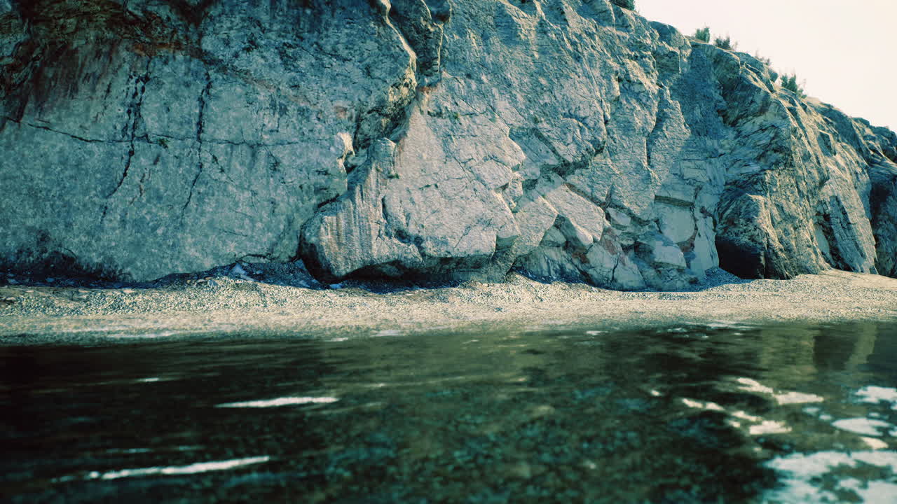 Clear water reflecting rocky shoreline under bright sunlight near coastal area