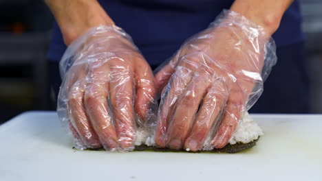 chef in gloves is preparing sushi. sushi are made of rice, nori seaweed, cucumber, cream cheese. appetizing and nutritious food concept.