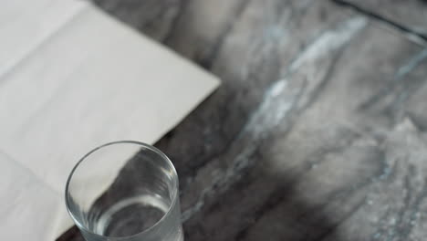 close up of three clear glass cups arranged neatly on marble countertop near folded white paper napkin under soft lighting, creating serene domestic kitchen scene with elegant minimalistic detail