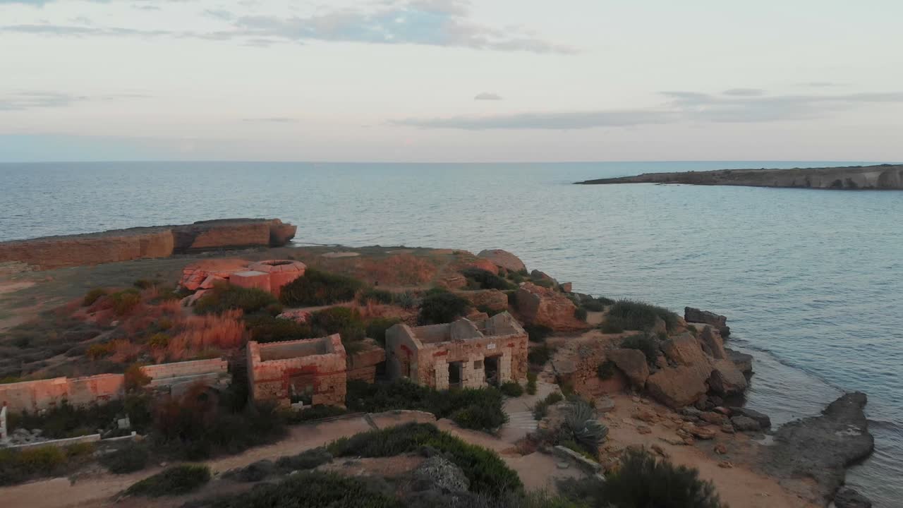 Siraküza, Sicilya, İtalya'da güzel gün batımında Punta della Mola plajında terk edilmiş ev ve sığınak havadan görünümü.
