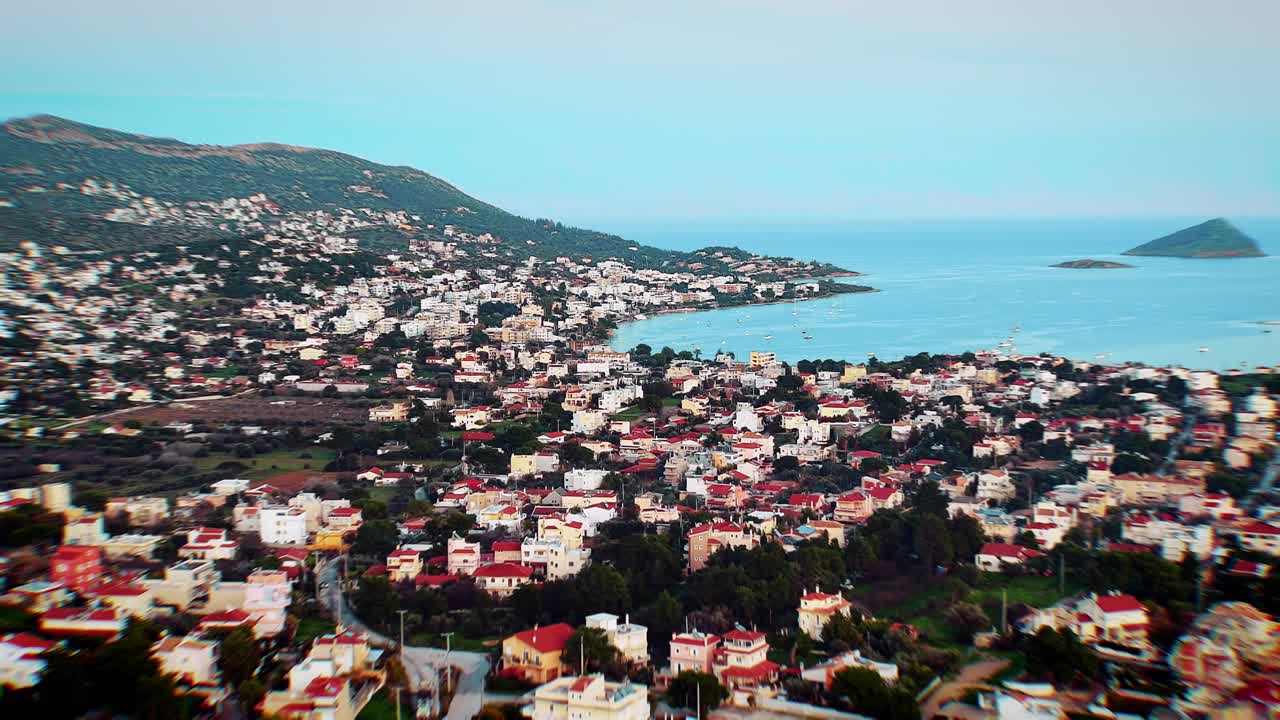 ~100 m de altitude com tempo bom. Céu azul vibrante encontra o mar azul cintilante; ilhas distantes pontilham o horizonte. Janeiro de 2026, costa da Ática: vista serena do Egeu