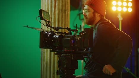 portrait of cameraman on railway trolley shooting green screne scene. professional crew on big budget filmmaking. on film studio set shooting historical movie green screen scene. slow motion arc shot