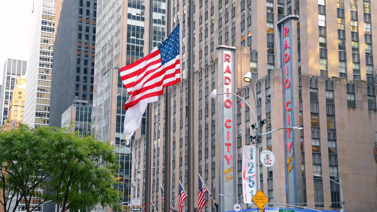 New York, USA, 16 luglio 2025: Radio City Music Hall e bandiere americane. Radio City Music Hall con bandiere americane che sventolano di fronte all'edificio a New York
