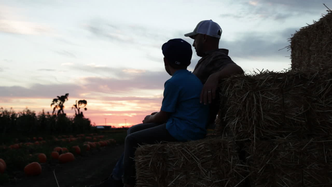 un padre y un hijo se sientan en un campo agrícola al atardecer 4