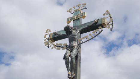 bronze crucifix with jesus christ statue against a cloudy sky
