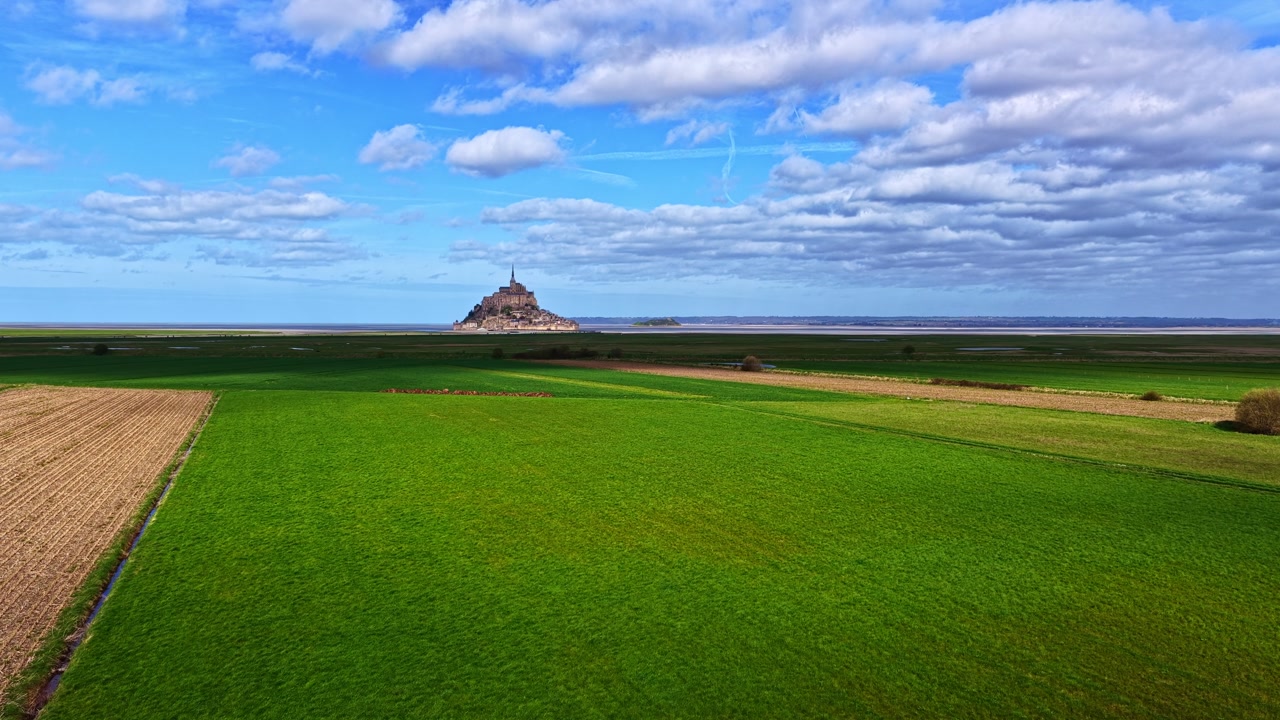 Mont Saint-Michel, a historic world heritage site in France viewed across flat fields and the bay
