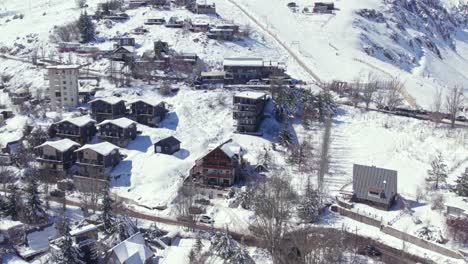 orbiting drone shot of european-style houses and cabins of the snow-filled village of farellones on a sunny, snowy day, chile