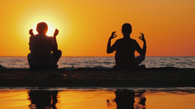 Abuela y nieta meditan en la playa. Concepto de personas mayores activas y saludables