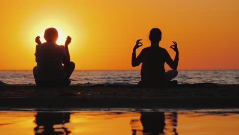 grandmother and granddaughter meditate on the beach active and healthy seniors concept