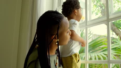 Side-view-of-young-black-mother-playing-with-his-son-on-window-sill-in-a-comfortable-home-4k