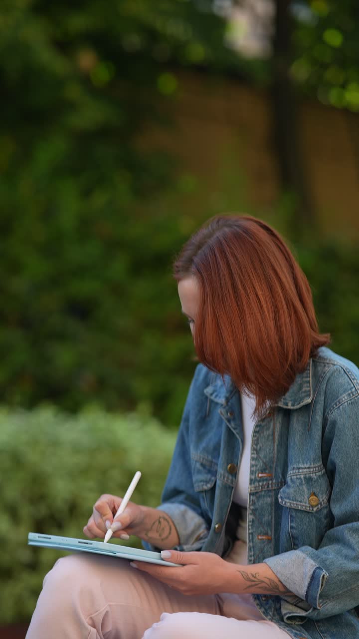 Donna che crea arte digitale su tablet all'aperto