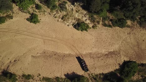 birds-eye view drone shot of a game vehicles in a dried up riverbed in the heat of the african afternoon sun