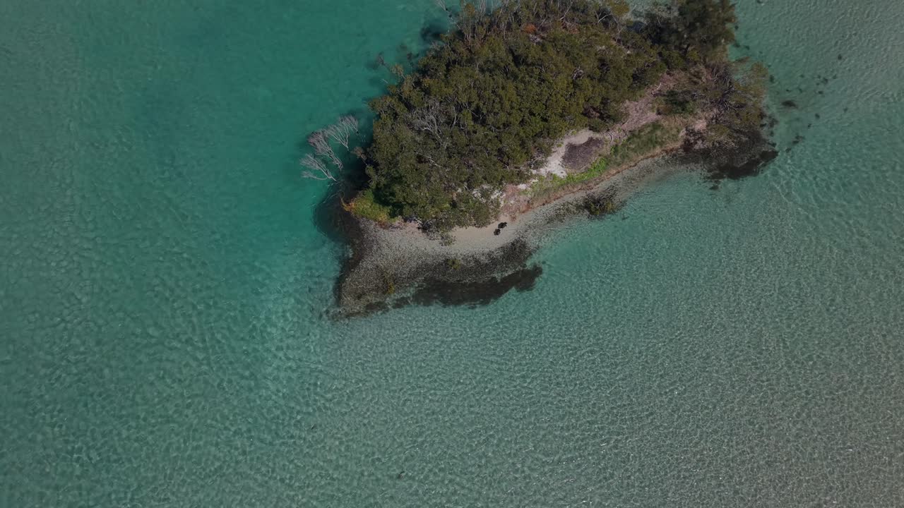 Calm turquoise sea flows around island point, aerial pullback reveals tropical oasis, Swansea Pirrita Island New South Wales
