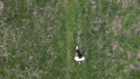 birds eye aerial view of young man doing somersault from standing position in outdoors, top down drone slow motion shot