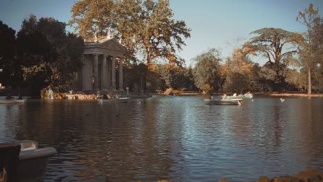 a small lake in the borghese park in rome, where people paddle in the lake