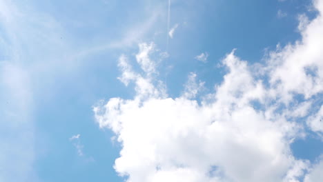 time lapse video capture in 24fps moving clouds with plane flies in the middle during a sunny day on blue background sky in city between buildings in fast speed