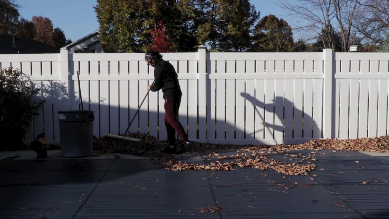 Gardener gathering fallen leaves to clean up the backyard on an autumn day