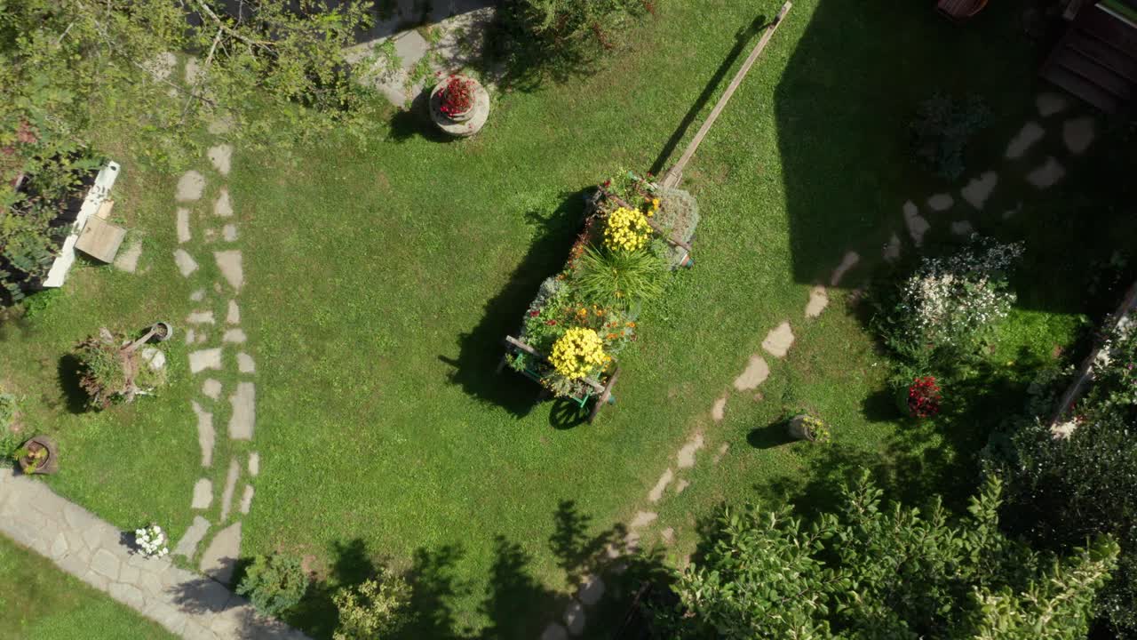 Garden flowers in ornamental wooden cart flower pot, rising aerial view